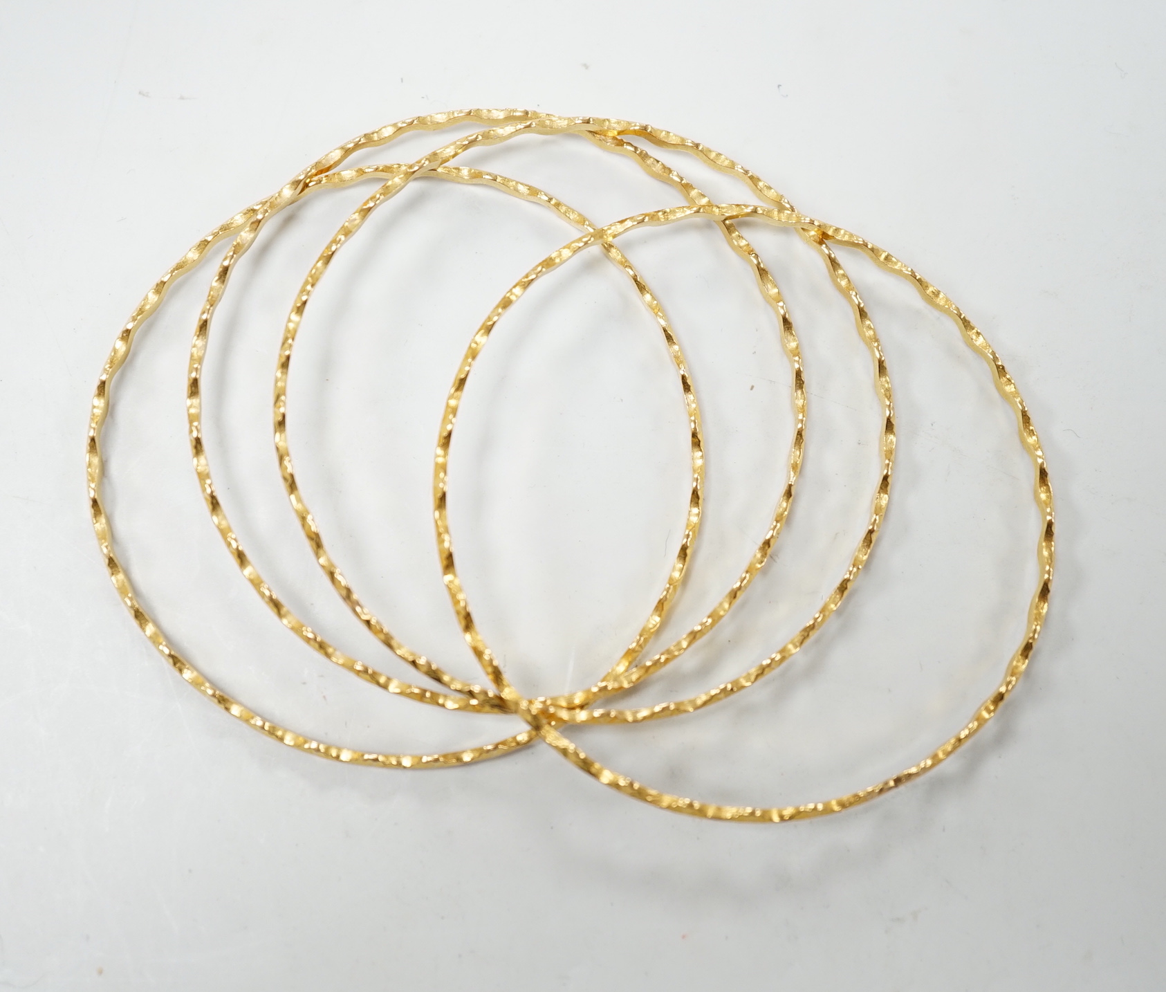 A set of four bright cut yellow metal bangles, with wavy border 34 grams.